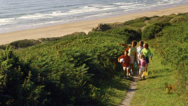 A family walking along the footpath at Woolacombe Beach, North Devon